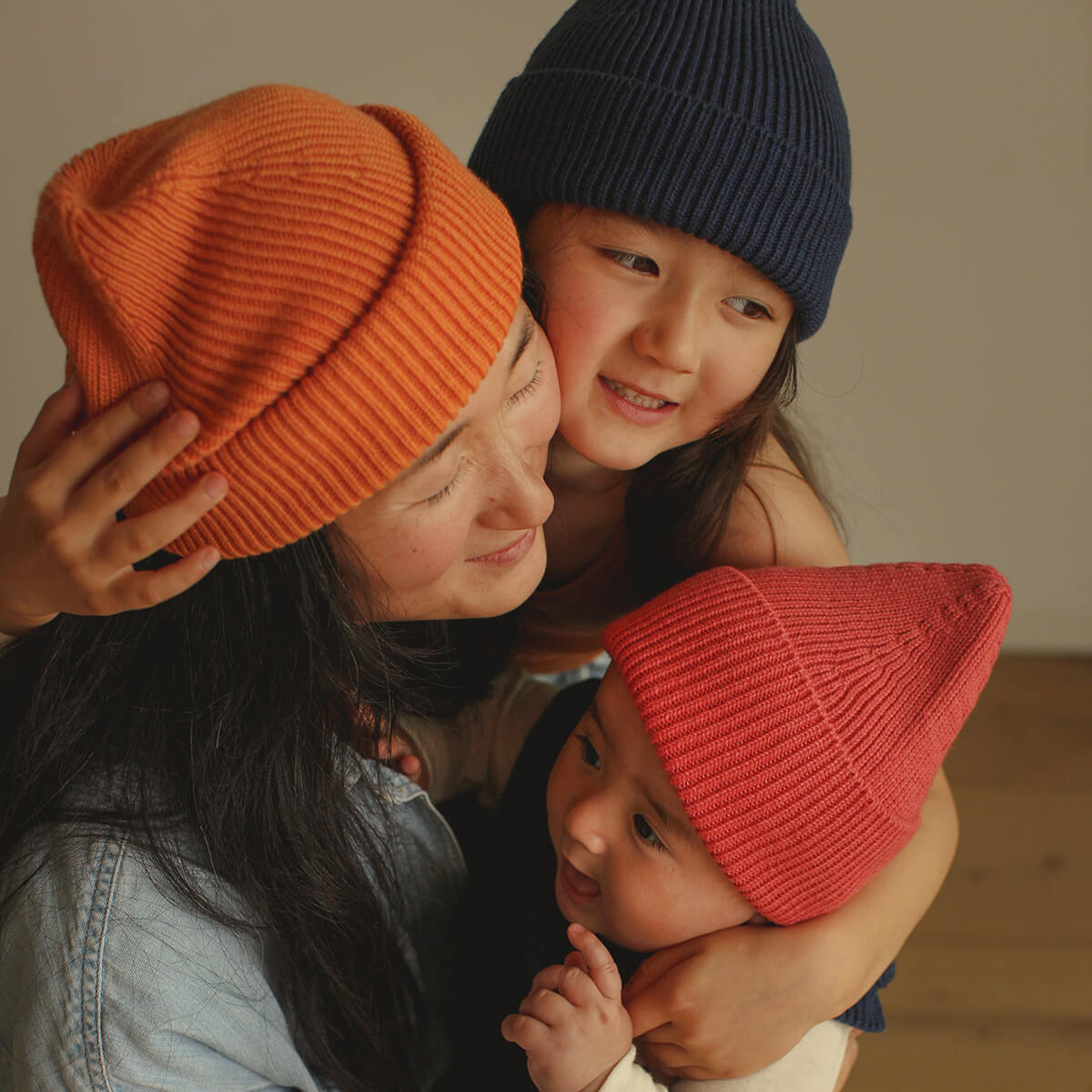 Mutter mit zwei Kindern trägt farbenfrohe Bio-Mützen – Black Week Kindermützen-Angebote bei LibertyKids