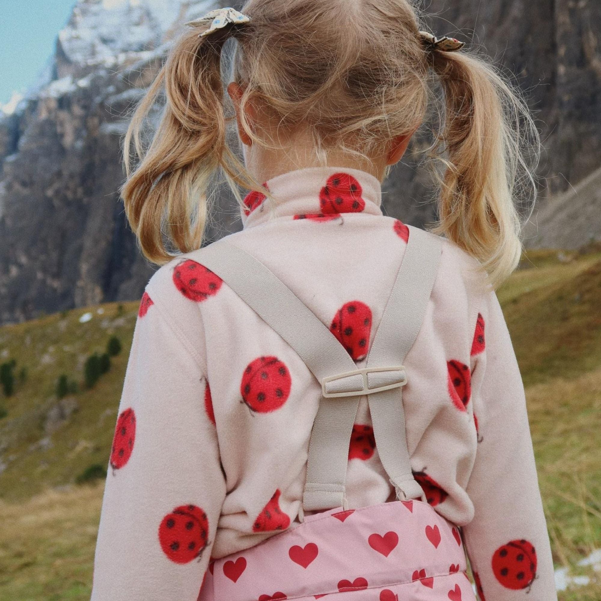 Mädchen mit Rucksack im Marienkäfer-Design von Konges Sløjd vor Bergkulisse