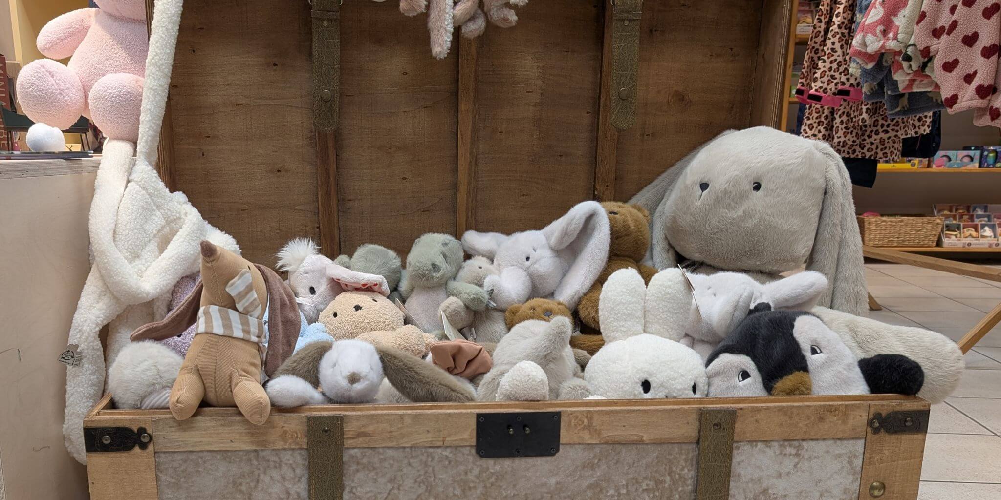 Eine Holzkiste voller kuscheliger Liewood Stofftiere in einem Kinderladen
