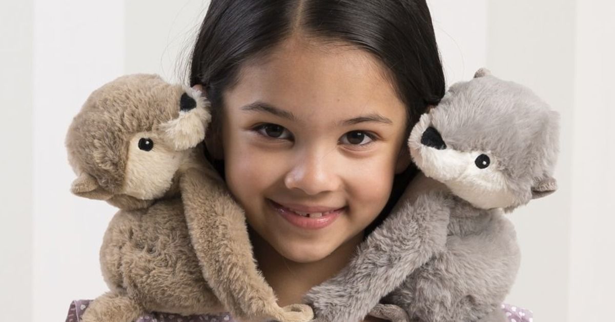 Kind mit zwei Warmies Otter-Wärmestofftieren auf den Schultern – mit Hirse-Lavendel-Füllung