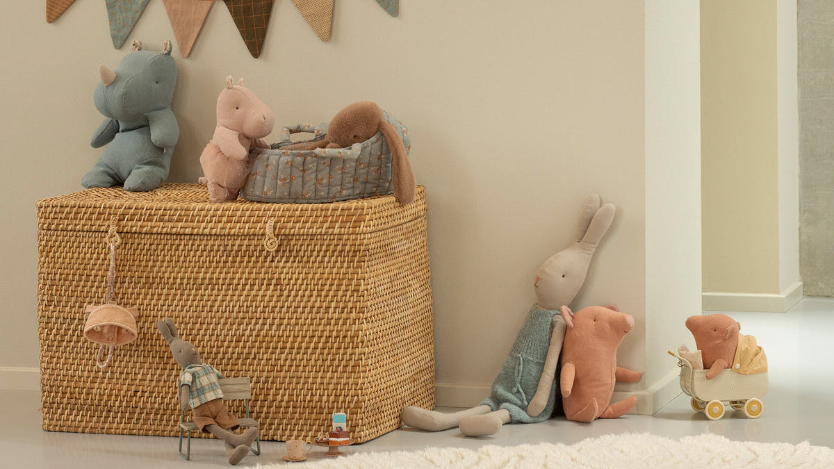 Nostalgische Maileg Babyzimmer-Deko mit einem geflochtenen Korb, einer Wimpelkette und kleinen Stofftieren.