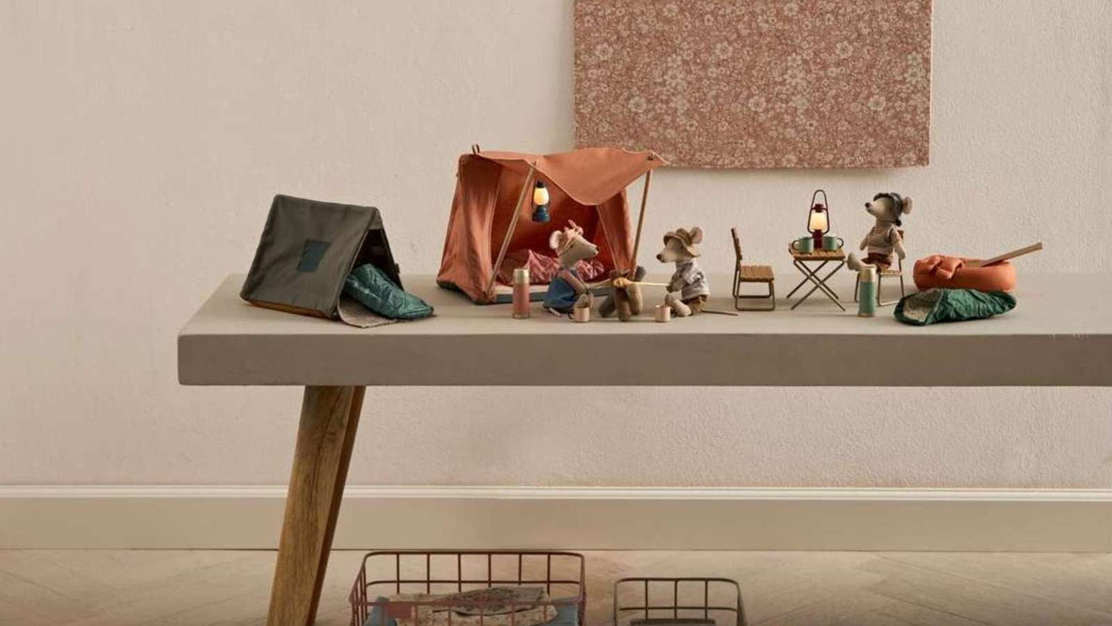 Eine Sammlung von Maileg Mäusen und Miniatur-Puppenhaus-Möbeln liebevoll auf einem kleinen Tisch arrangiert.