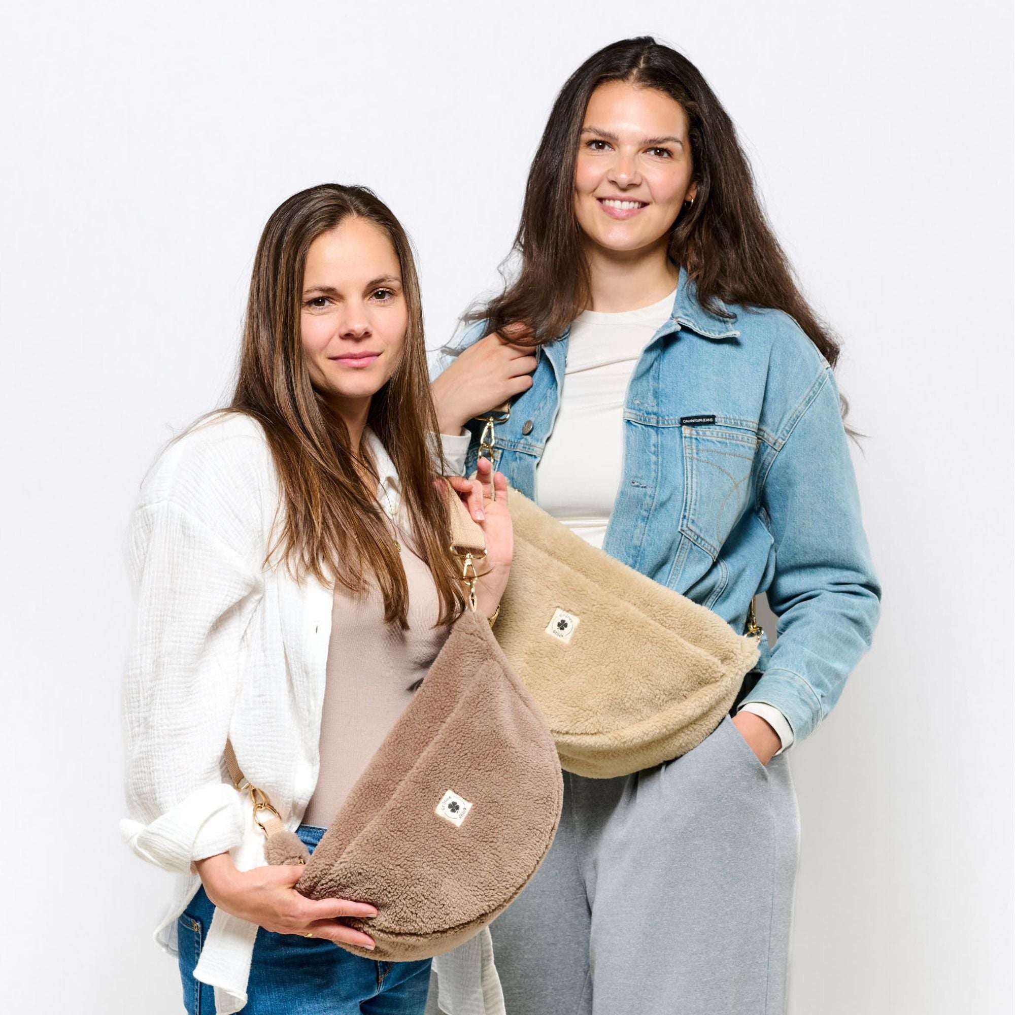 Zwei Frauen präsentieren LibertyKids Felltaschen in verschiedenen Farben und Mustern – stylisch und praktisch für Mamas